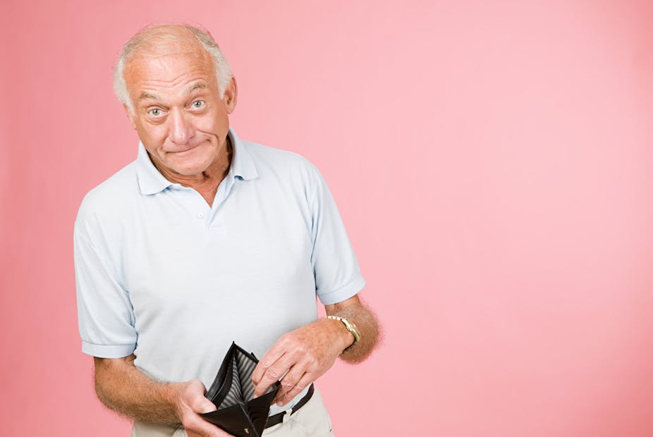 A man with a chagrined expression displays an empty wallet.