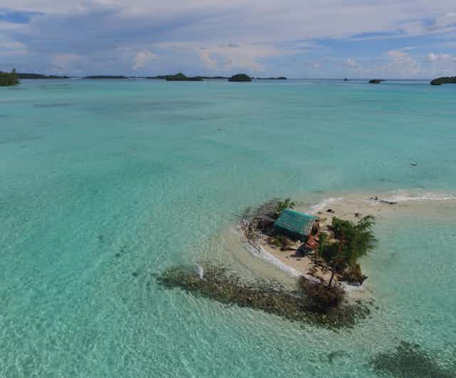 Fotografia aérea mostrando a água do mar cercando uma cabana e árvores em uma pequena ilha, para ilustrar o impacto do aumento do nível do mar nas Ilhas Salomão