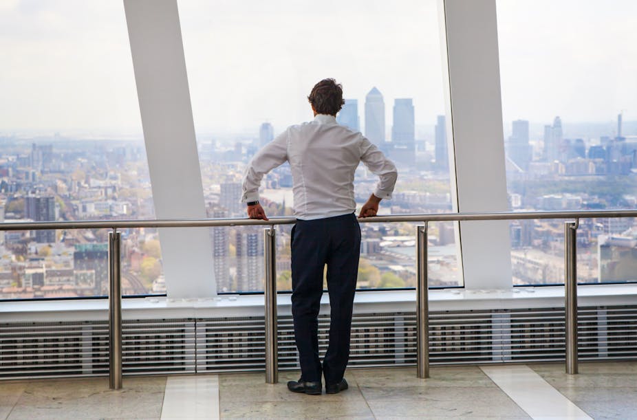 Man in suit looks out over City of London skyline