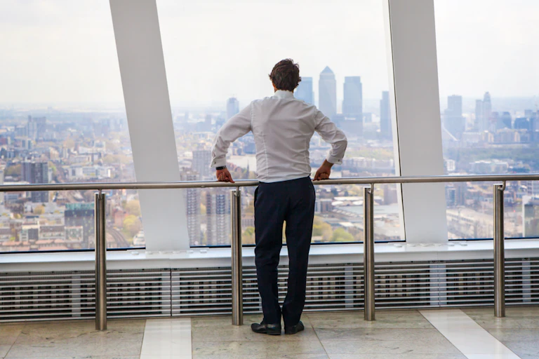 Man in suit looks out over City of London skyline