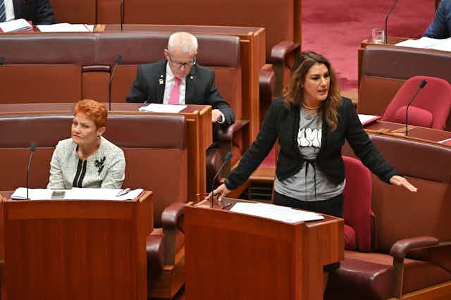 Senator Pauline Hanson sits in parliament while Senator Lidia Thorpe stands and is addressing parliament.