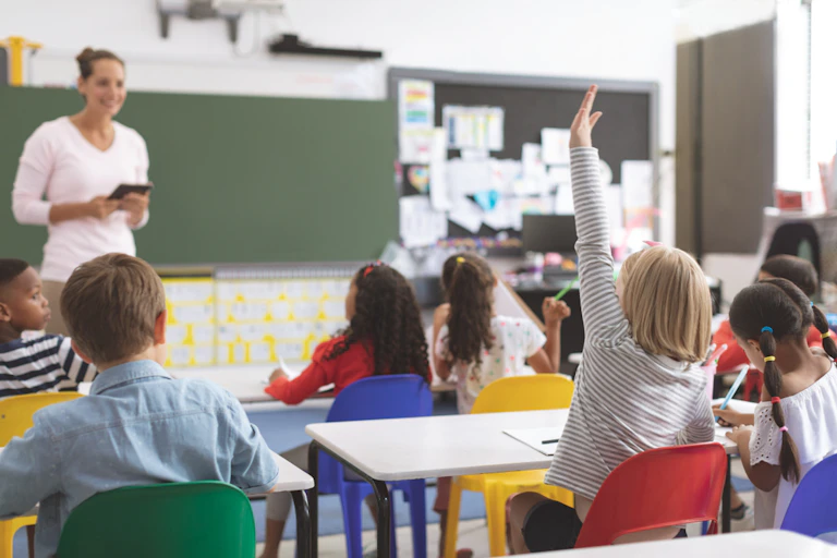 Ecolière levant la main en classe avec ses camarades autour d'elle
