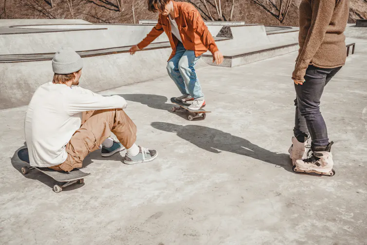 Trois adolescents discutant dans un skatepark