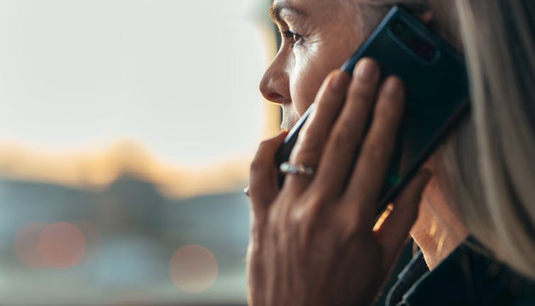 Close up side profile of a middle aged woman talking on a mobile phone