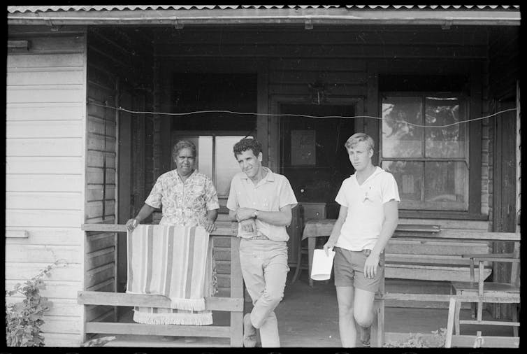 An older woman and two young men wearing badges.