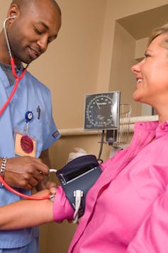 Male nurse takes a woman's blood pressure
