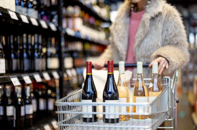 woman shops for wine, pushes trolley