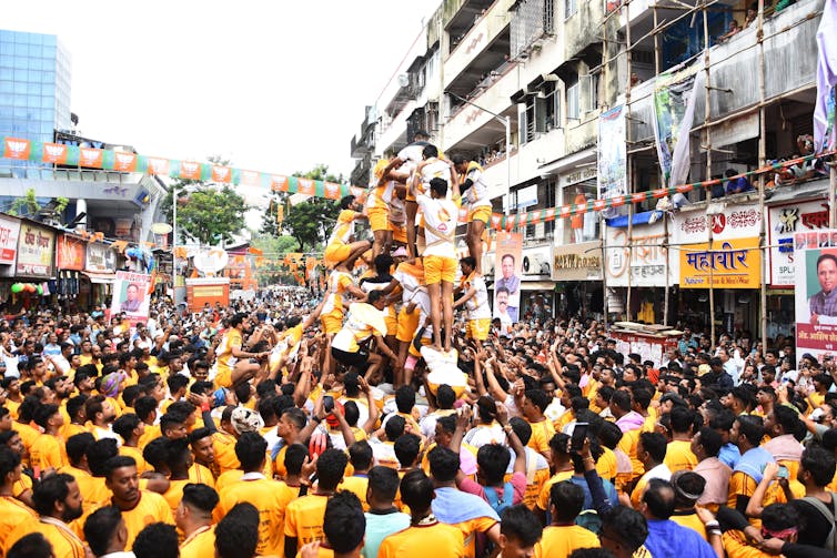A number of young men, dressed in yellow shorts, forming a human pyramid.