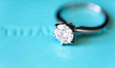 A diamond engagement ring on a Tiffany blue background.