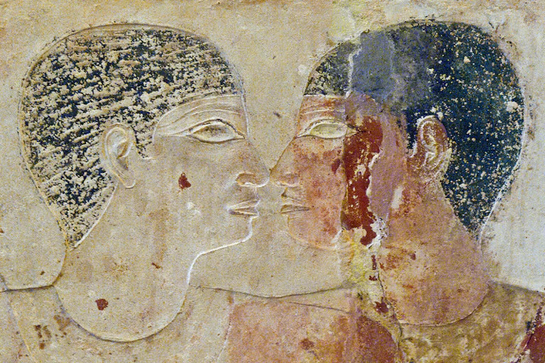 A faded mural depicting two men looking into each other's eyes with their faces very close to each other.