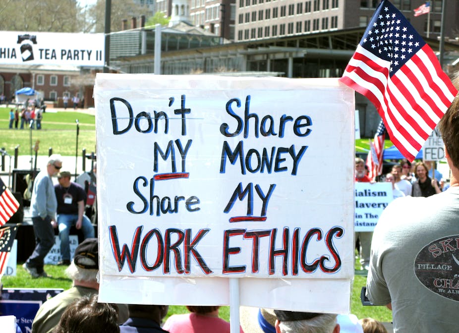 Lors d'une manifestation avec des drapeaux américains, on voit une pancarte proclamant « Don't share my money, share my work ethics ».