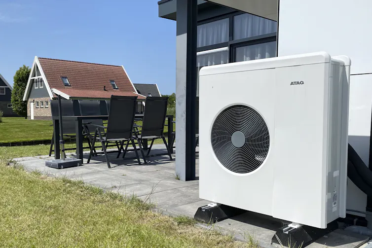 A heat-pump unit seen in the foreground of a house.