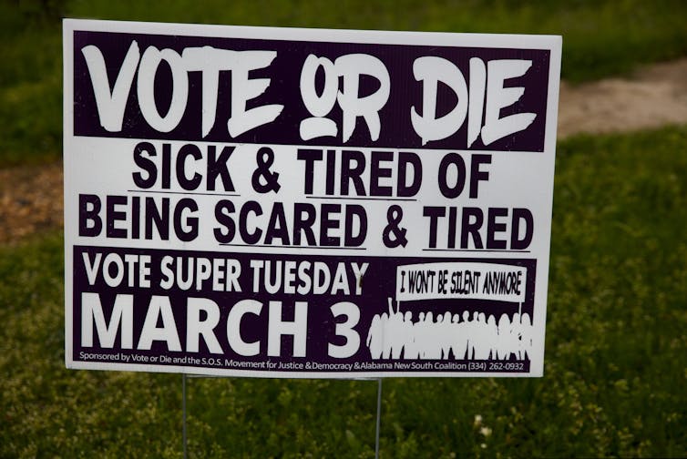 A black and white poster urges Black residents to vote.