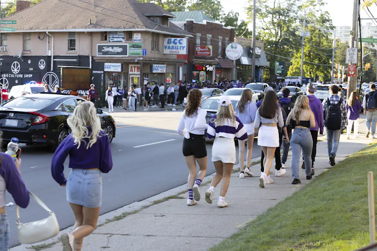 Crowds of students seen walking through a neighbourhood.