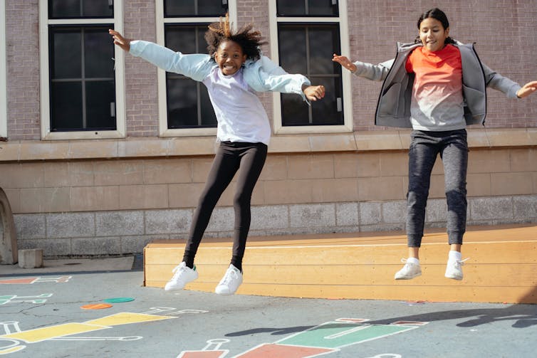 Two students jump in the playground.
