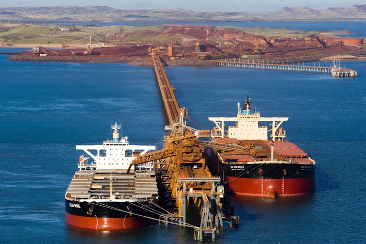 Large container ship docked and being loaded with iron ore for export