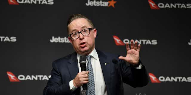 Man speaks in front of Qantas logos