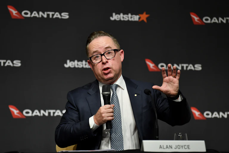 Man speaks in front of Qantas logos