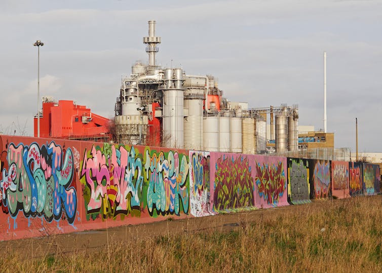 A graffit-sprayed wall outside a factory.