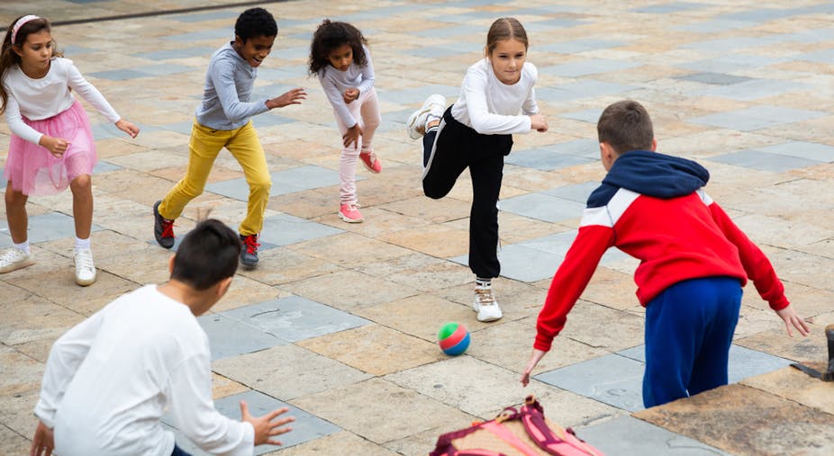 Enfants jouant avec une balle dans une cour de récréation