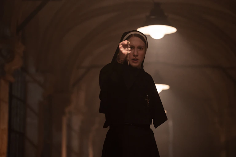 A young nun in her black habit holding her crucifix up