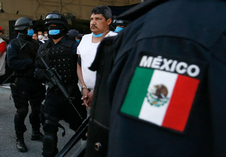 Uniformed police surround an arrested man in Mexico City