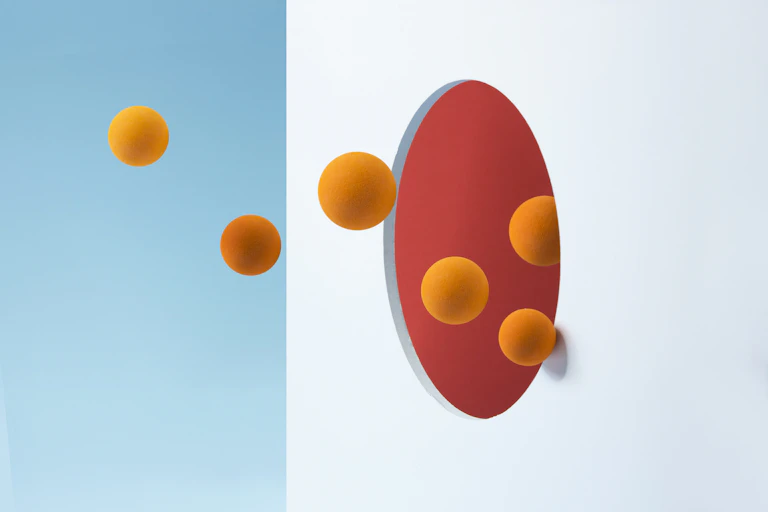 Illustration of orange spheres entering a hole in a white wall with a red interior
