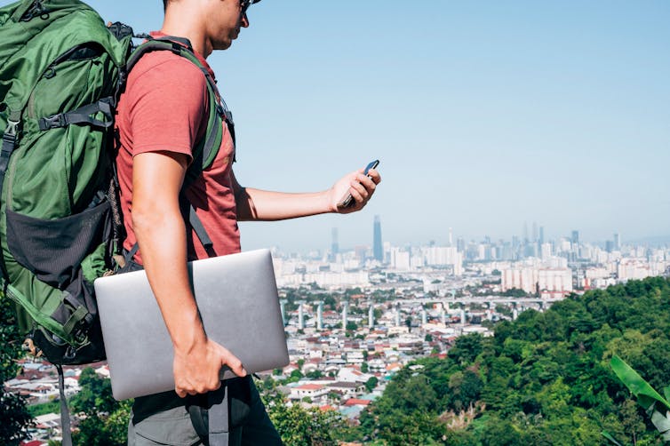 A backpacker carrying a laptop and smartphone.