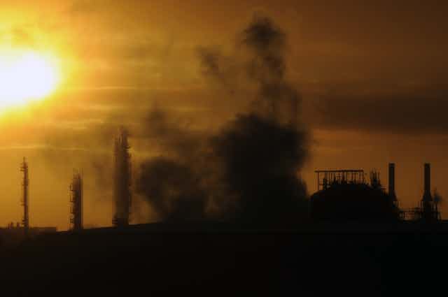sun rises over smoke emerging from an industrial plant