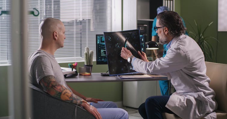 A doctor explains an x-ray to a male cancer patient.