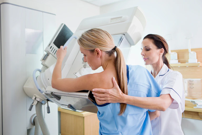 A middle-aged woman has a mammogram performed by a female nurse.