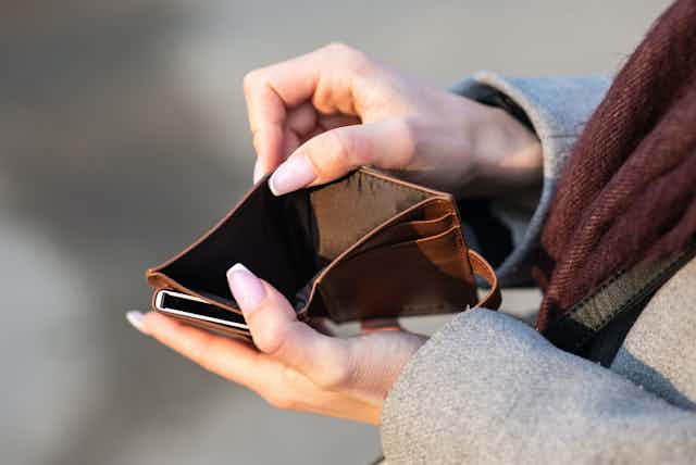 Two hands holding an empty wallet open.
