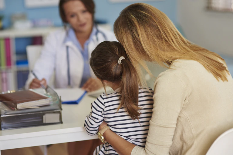 A mother and her young child speak to a female doctor.