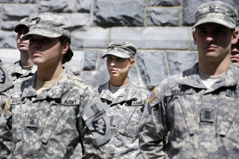 Two male and two female cadets in U.S. army camouflage stand at attention.