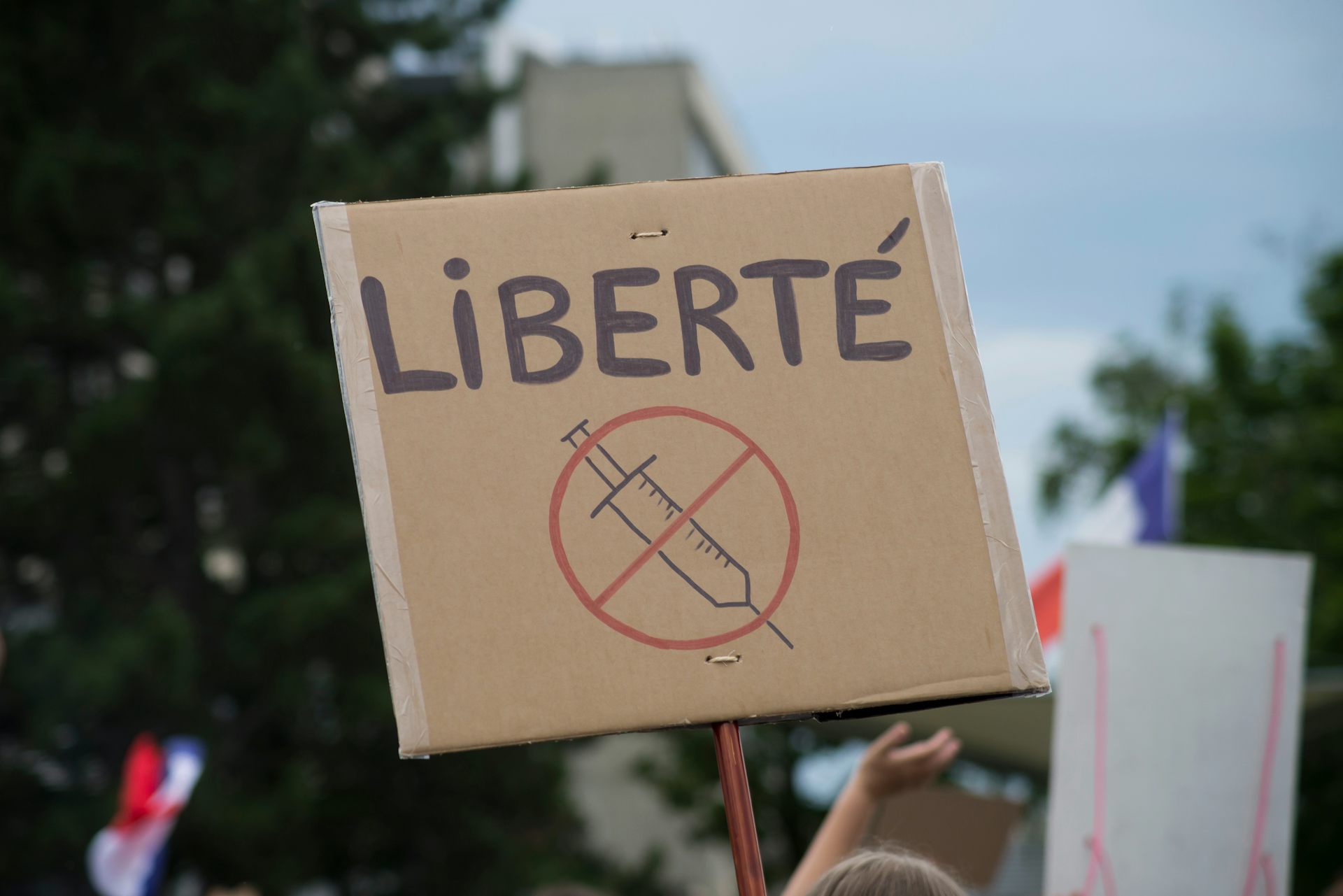 Photo d’une pancarte comportant une seringue barrée et le mot « liberté » en majuscules