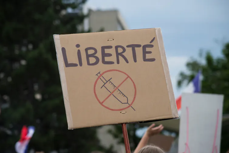 Photo d’une pancarte comportant une seringue barrée et le mot « liberté » en majuscules