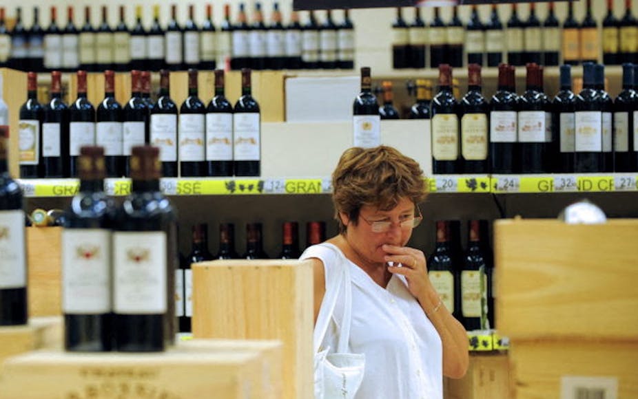 Personne hésitante dans un supermarché lors d'une foire aux vins. 