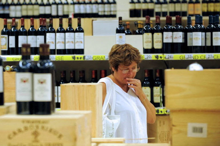 Personne hésitante dans un supermarché lors d'une foire aux vins.