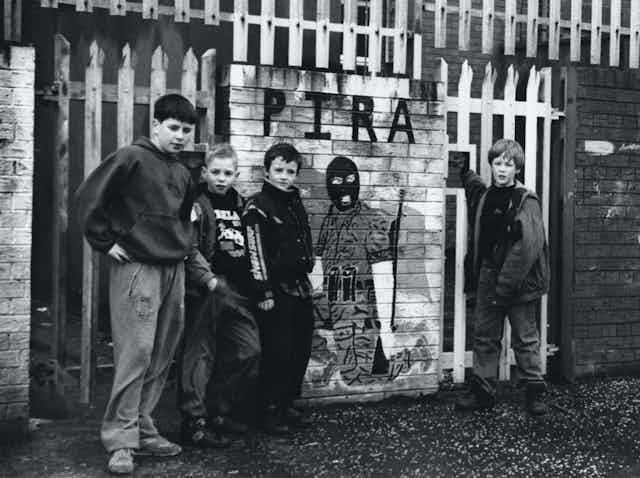 Niños posan junto a un mural callejero en honor a los miembros del IRA Provisional (PIRA), un grupo armado escindido del IRA, en Belfast.