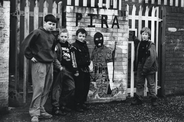 Niños posan junto a un mural callejero en honor a los miembros del IRA Provisional (PIRA), un grupo armado escindido del IRA, en Belfast.