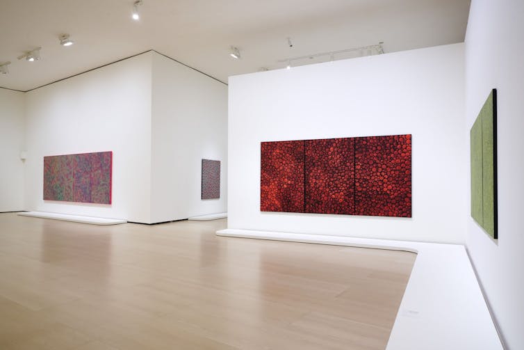 Imagen de una sala de un museo con pinturas de gran tamaño en las que se repiten los mismos patrones.