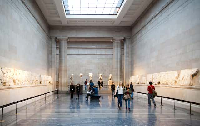 Visitantes pasean junto a los Mármoles del Partenón en el Museo Británico. 