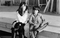 Black and white photo of a woman sitting on a curb with a little boy.