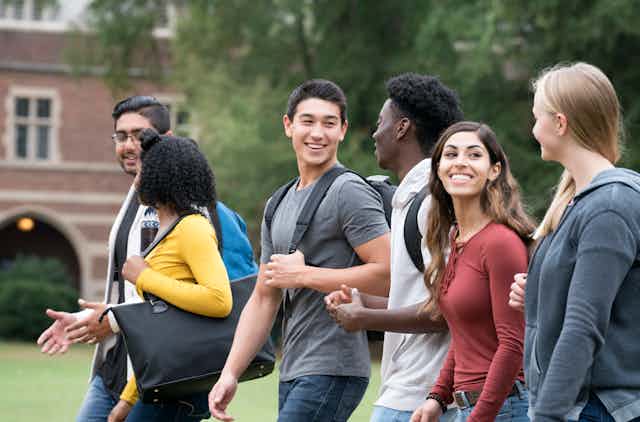 Six college students walk and talk on campus.