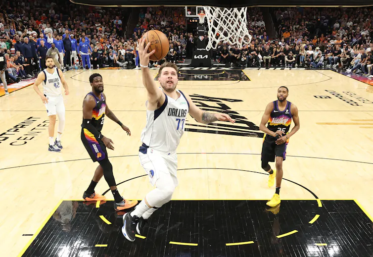 Basketball players jumping towards the net
