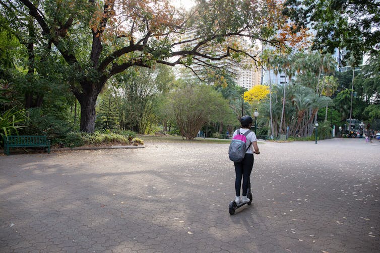 A person riding an electric scooter through a botanical garden