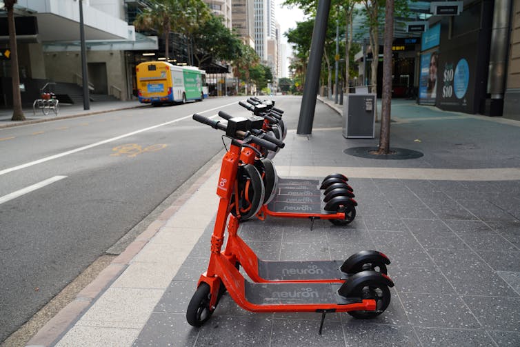 Electric scooters lined up at the edge of a city street
