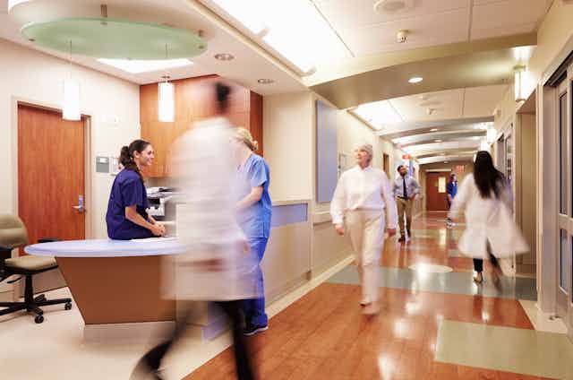 Busy hospital corridor with doctors and nurses blurred, moving fast