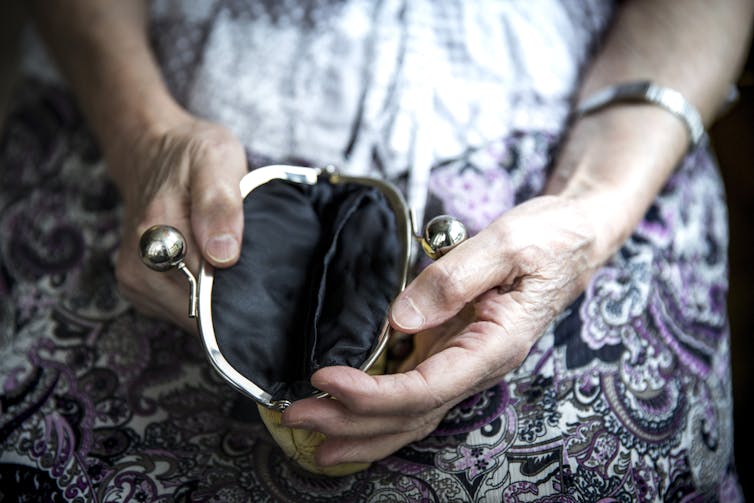 Elderly woman with empty purse in lap