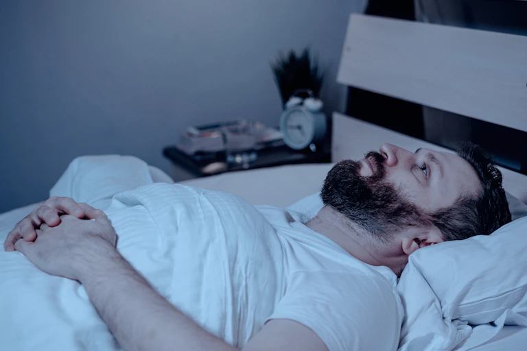 A man lies in bed waiting to fall asleep.